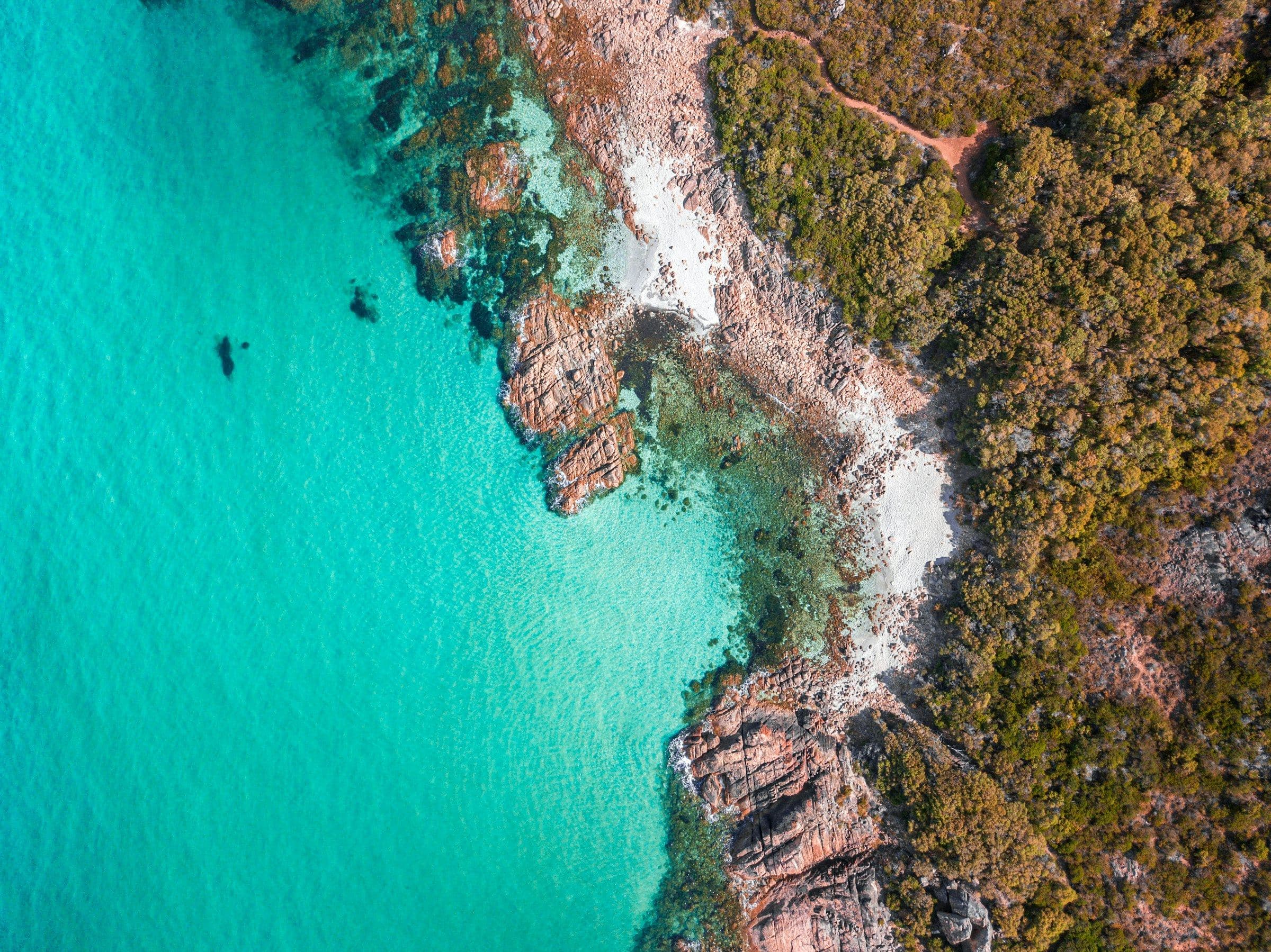 Turquoise water against a rocky bush headland in Western Australia, from above